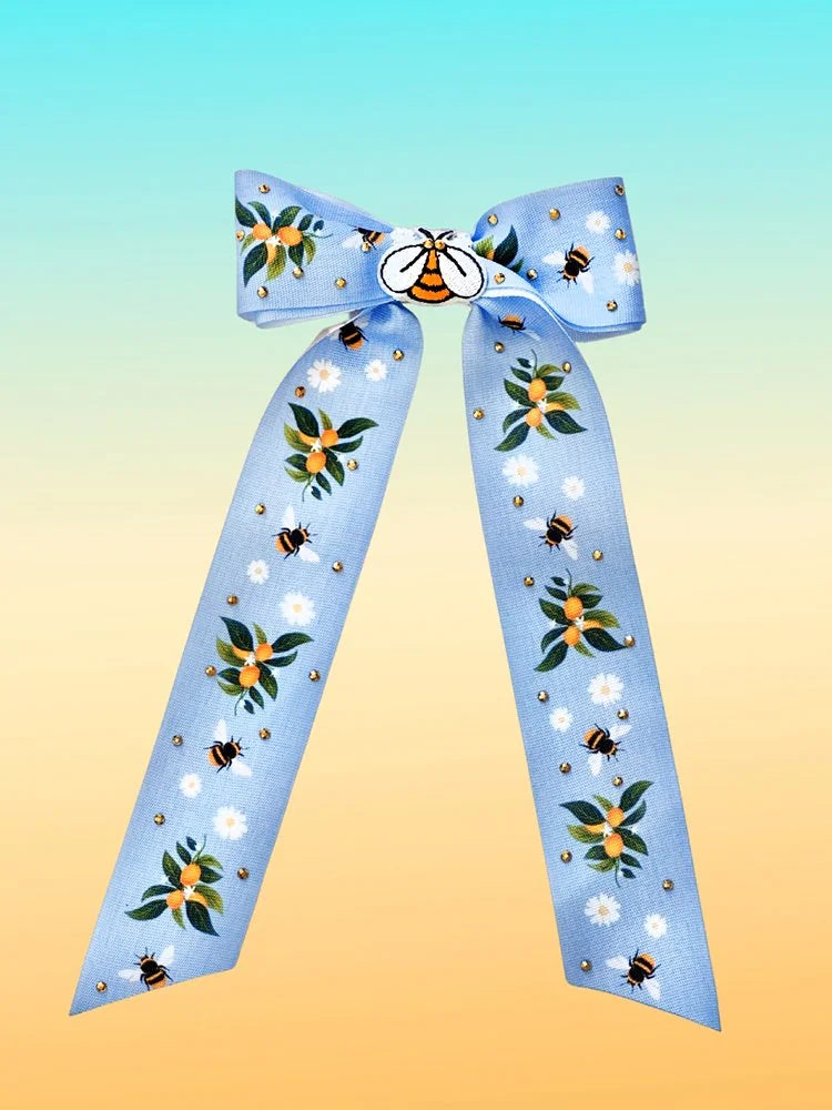 Front view of the Lemon Bee hair bow with blue lemon-and-bee print fabric and gold rhinestones.