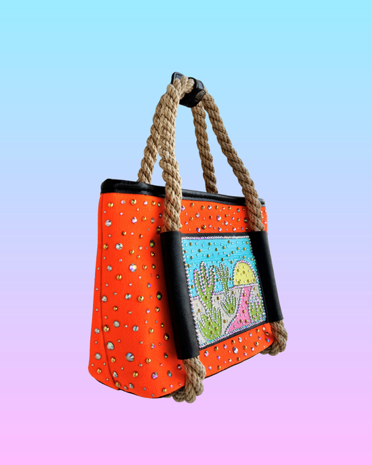 Side view of the High Noon Mini Tote showing neon orange body, rhinestones, and rope handles.