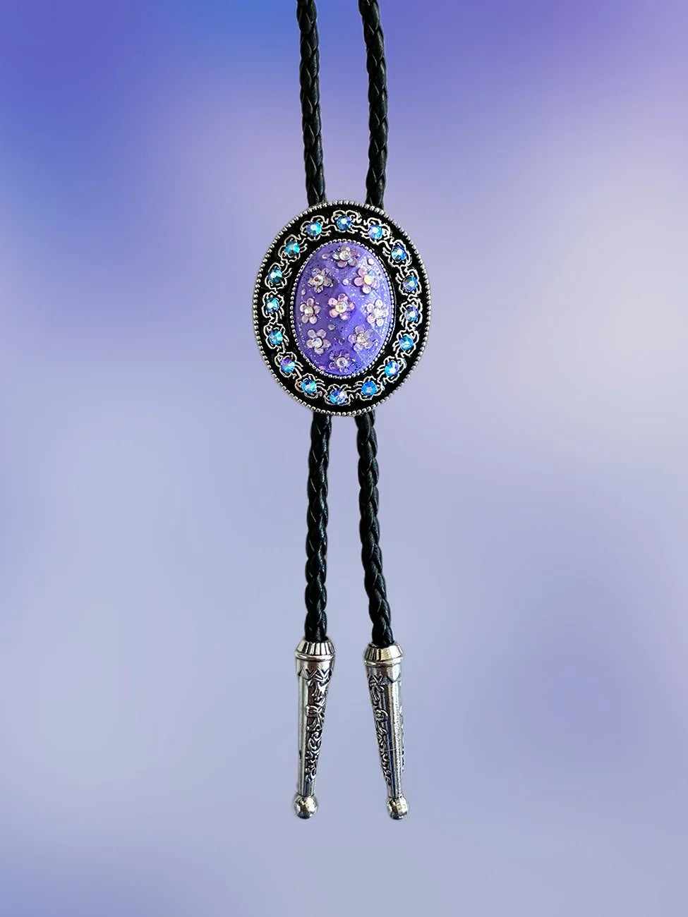 Front view of the Moonlit Violet Bolo Tie with violet floral pendant, purple rhinestones, and silver tips on braided black rope.