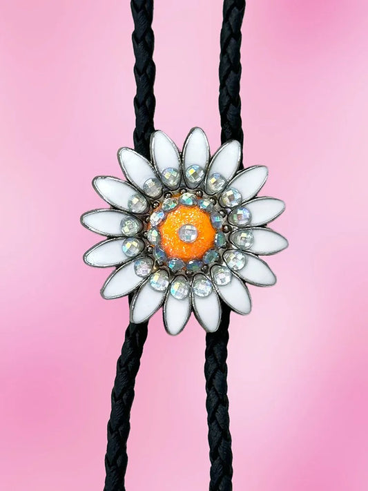 Closeup view of the Neon Daisy Bolo Tie featuring a white petal daisy with a glittery neon orange center and iridescent rhinestones.