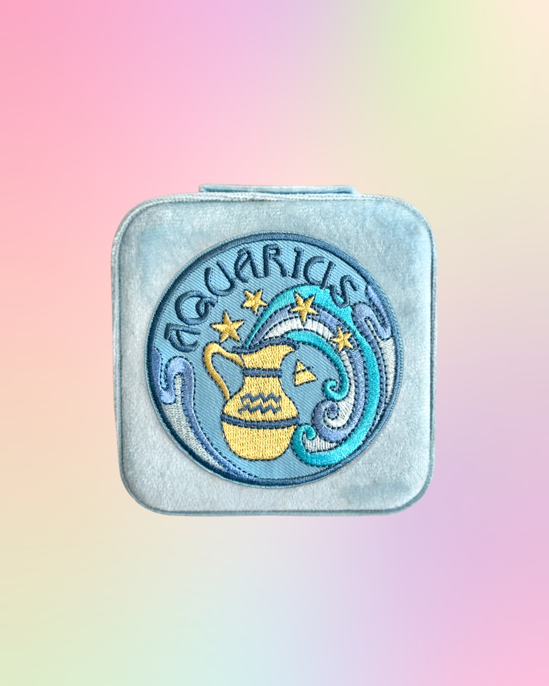 Aquarius zodiac sign design on a square, light blue, jewelry case on a gradient background.