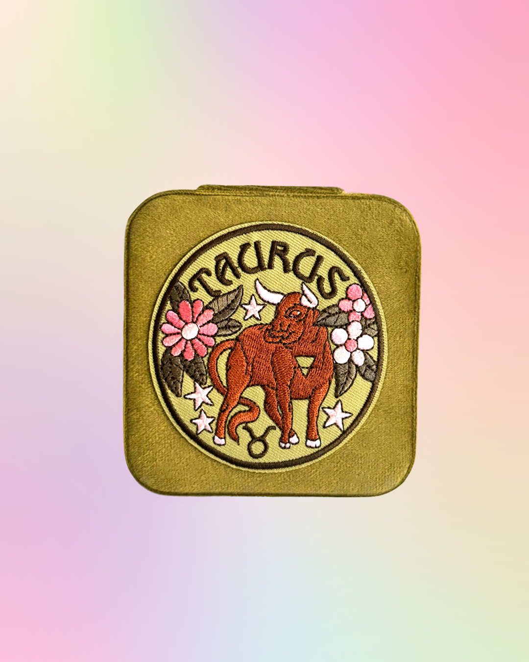 Taurus zodiac sign design on a square, green, jewelry case against a pastel gradient background.