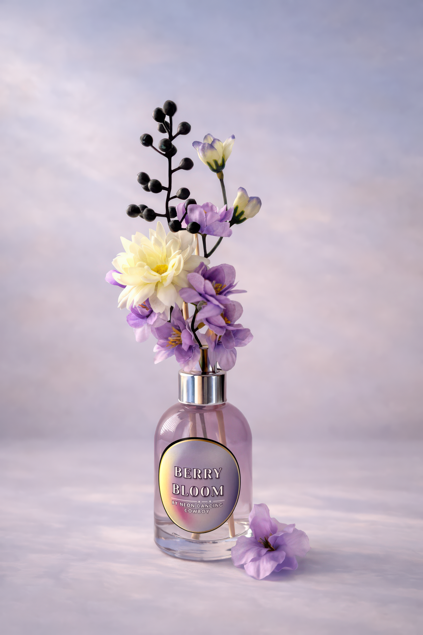 Berry Bloom reed diffuser in a clear glass bottle with purple liquid and lavender stems against a pastel background.