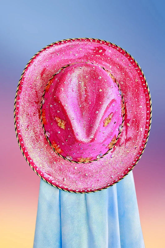 Magenta cowboy hat with butterflies, rhinestones, and black-and-gold trim, top view.