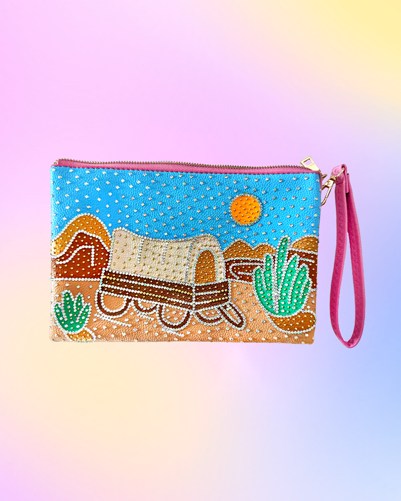 Front view of wristlet featuring hand-painted covered wagon desert scene and rhinestones.