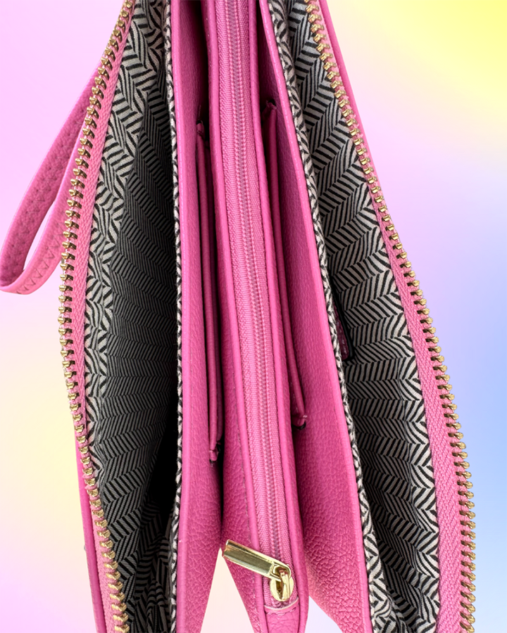Interior view of pink wristlet showing three compartments and patterned lining.