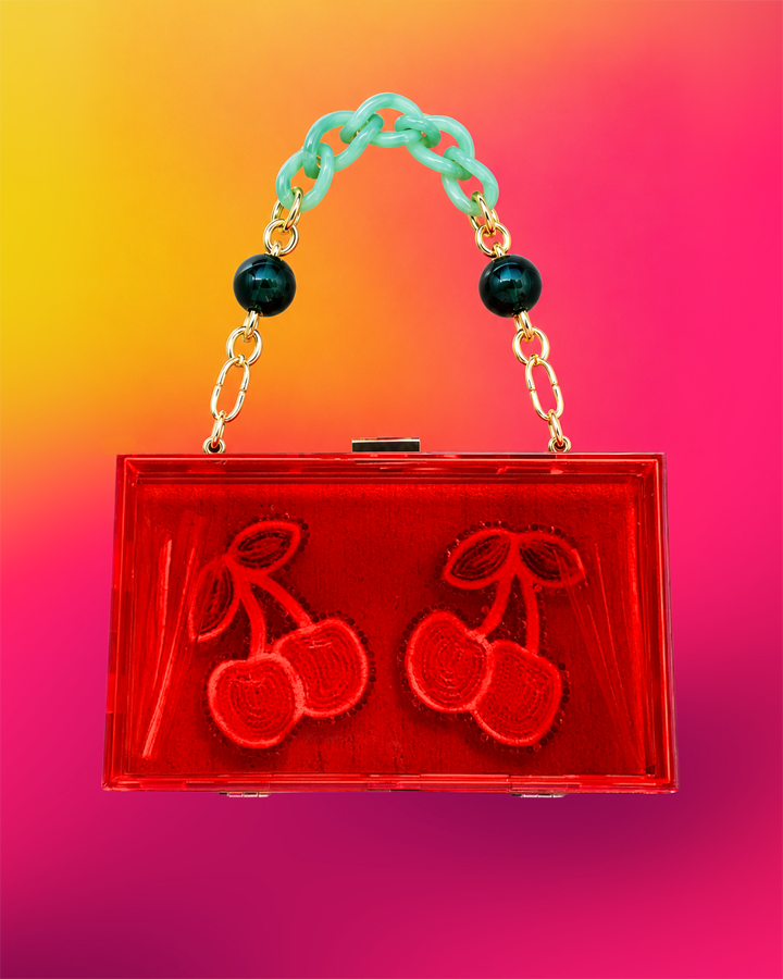 Back of red acrylic clutch with cherry motif.