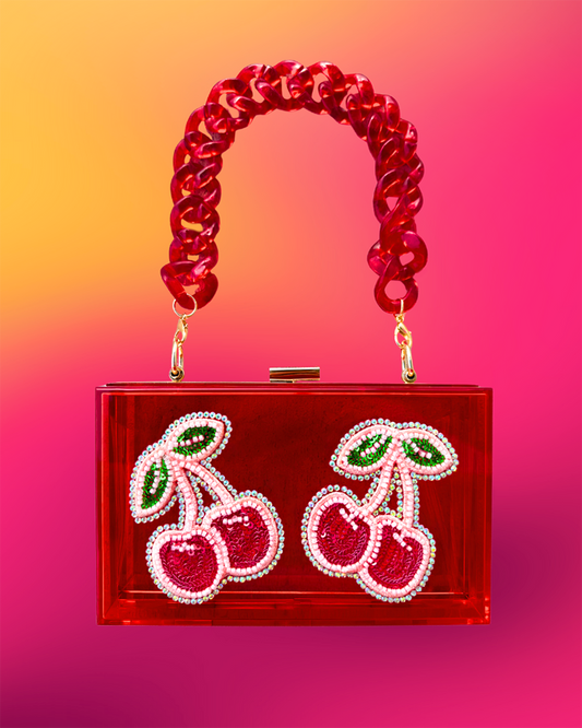 Front view of red acrylic clutch with beaded cherry motifs and resin strap.