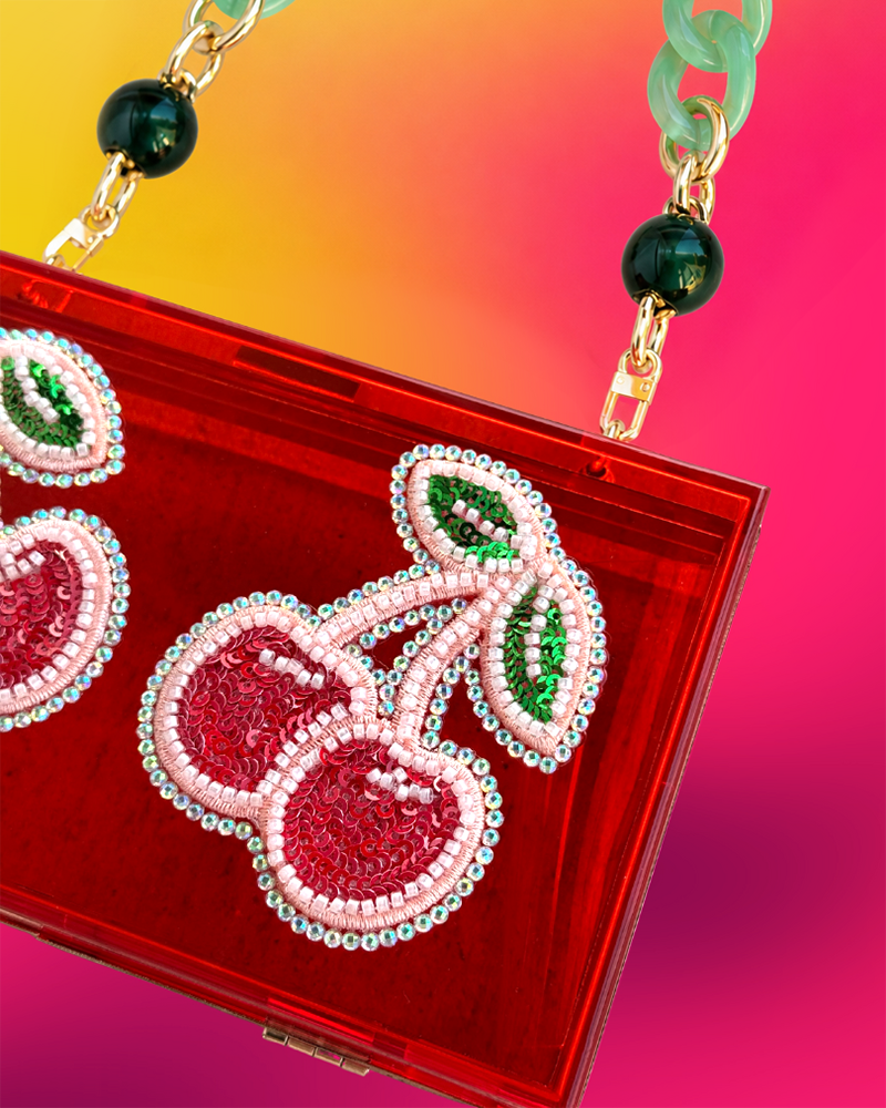 Close up of red acrylic clutch with cherry motif.