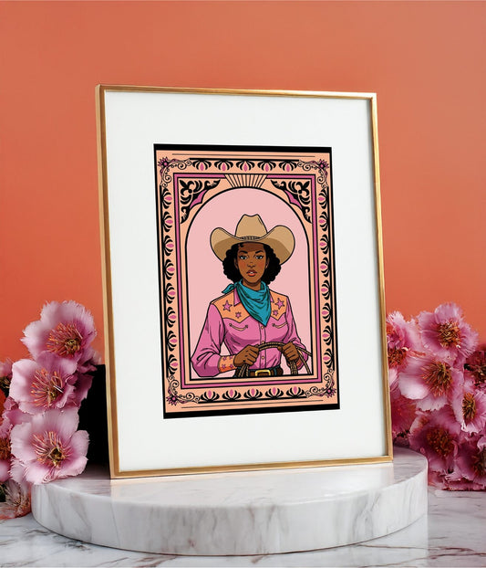 Framed cowgirl art print displayed on a round marble stand with pink flowers on a orange background.