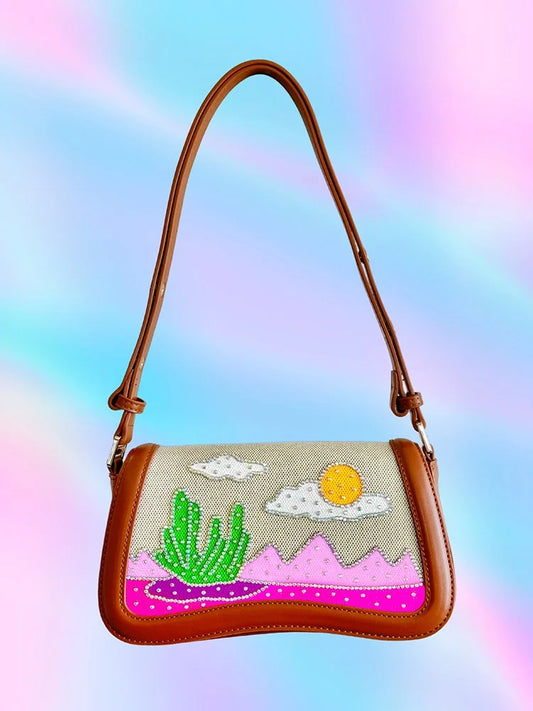 Front view of brown vegan leather handbag with hand-painted desert scene and rhinestone details.