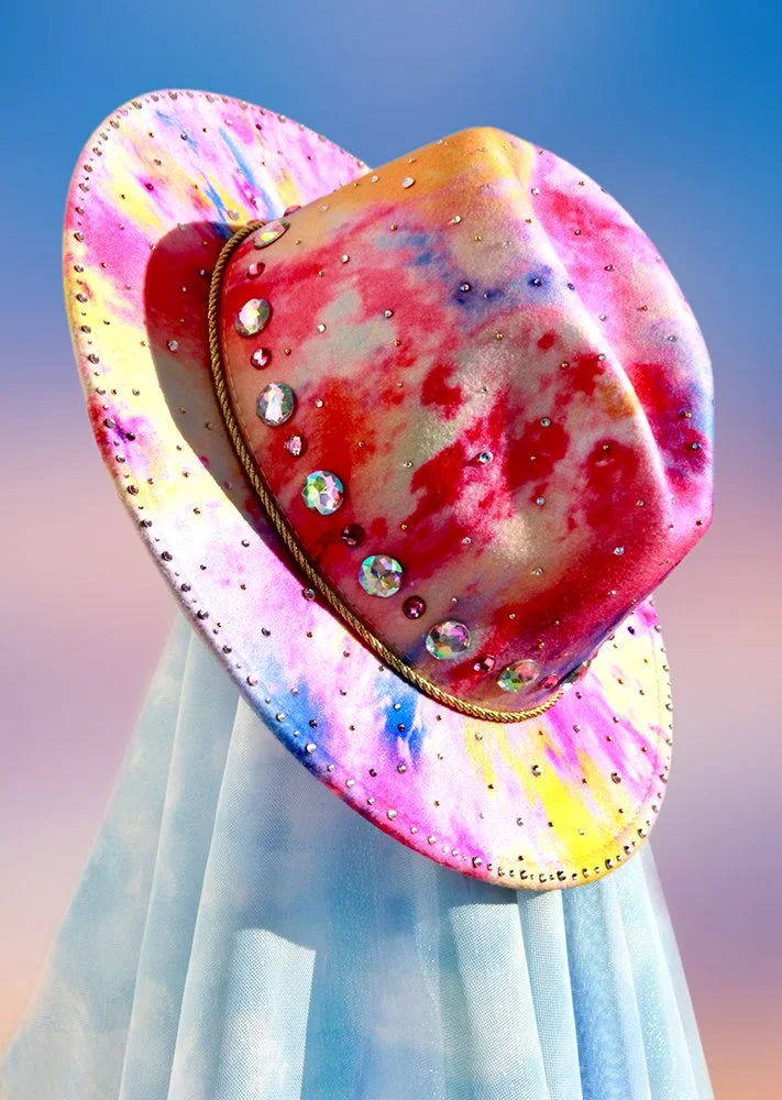 Multicolor tie-dye felt fedora with oversized iridescent gems and gold rope band, front angled view.