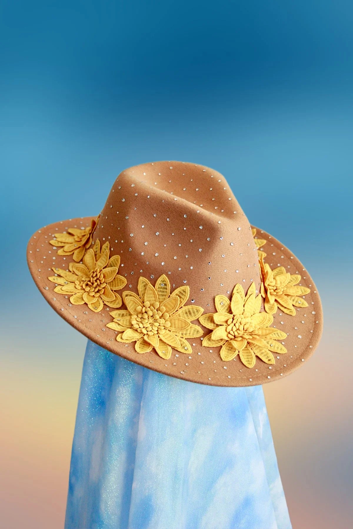 Front view of tan embellished fedora decorated with bright yellow flowers.
