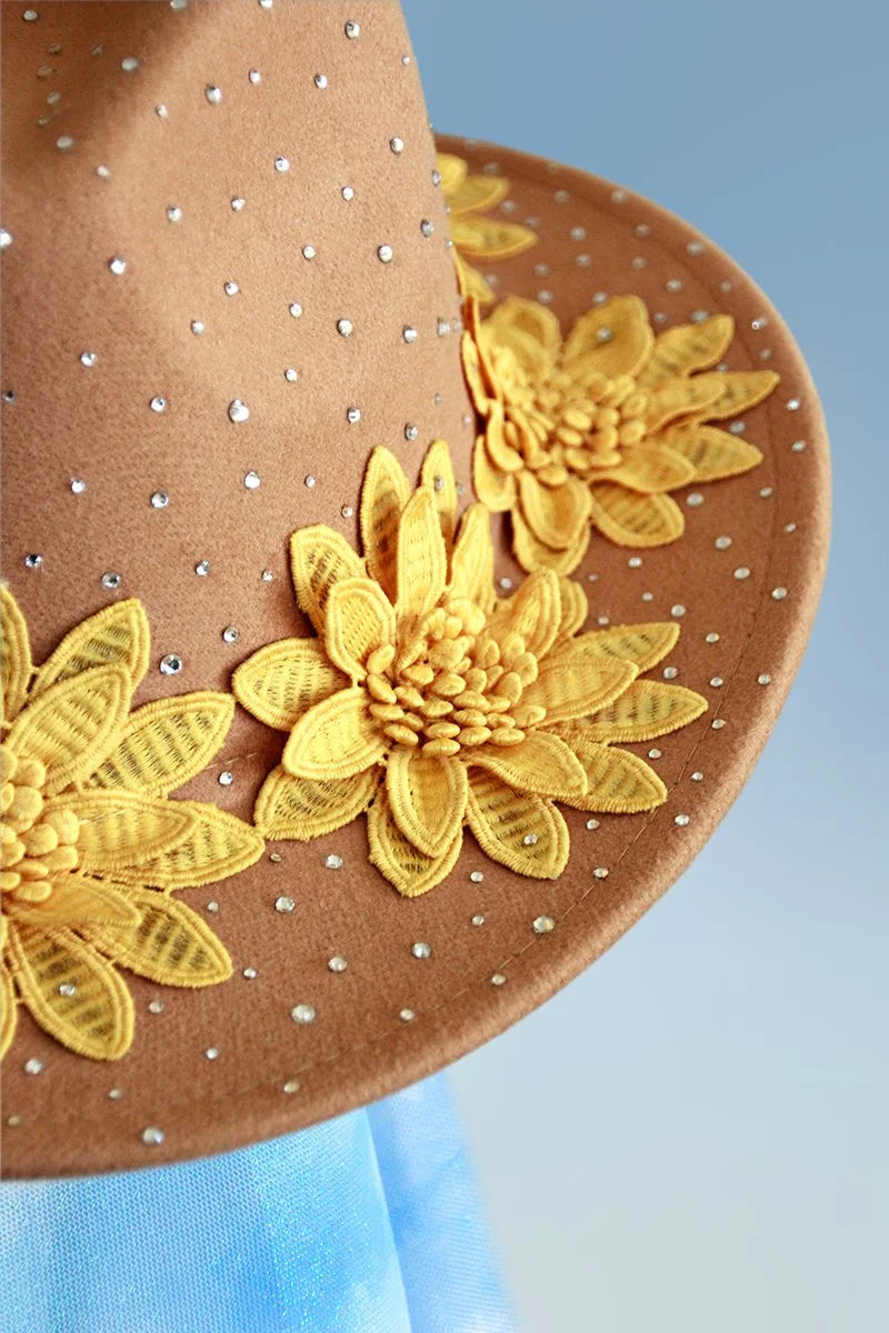 Close-up of yellow floral appliqués and scattered rhinestones on tan brim.