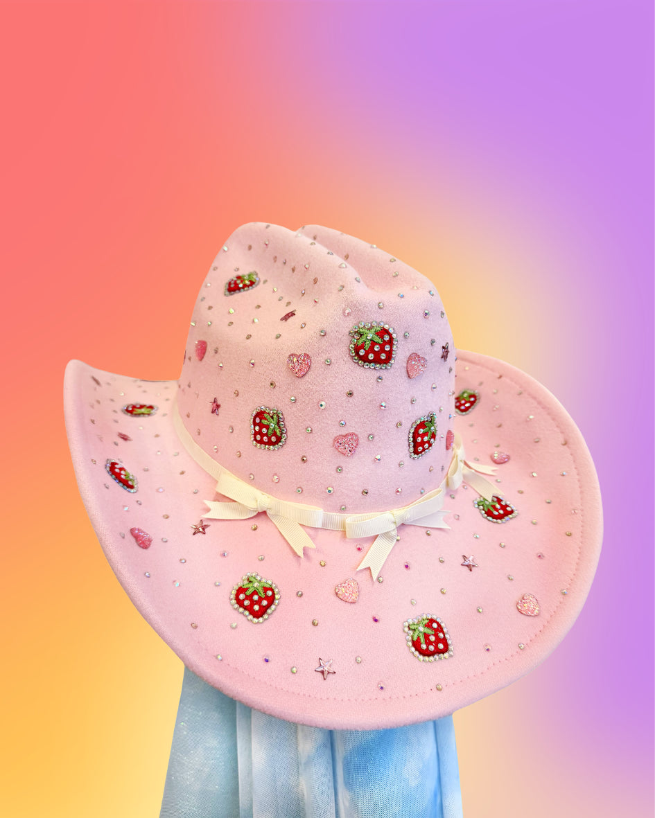Front view of the Berry Belle cowboy hat in baby pink with strawberry accents, rhinestones, and ribbon bow embellishments.