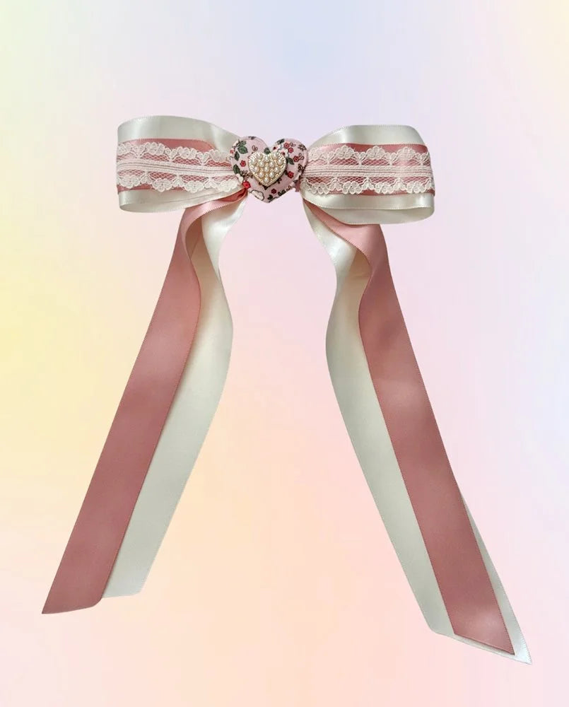 Front view of the Blushing Belle hair bow with dusty pink satin ribbon, white lace layers, floral heart center, and gold accents.