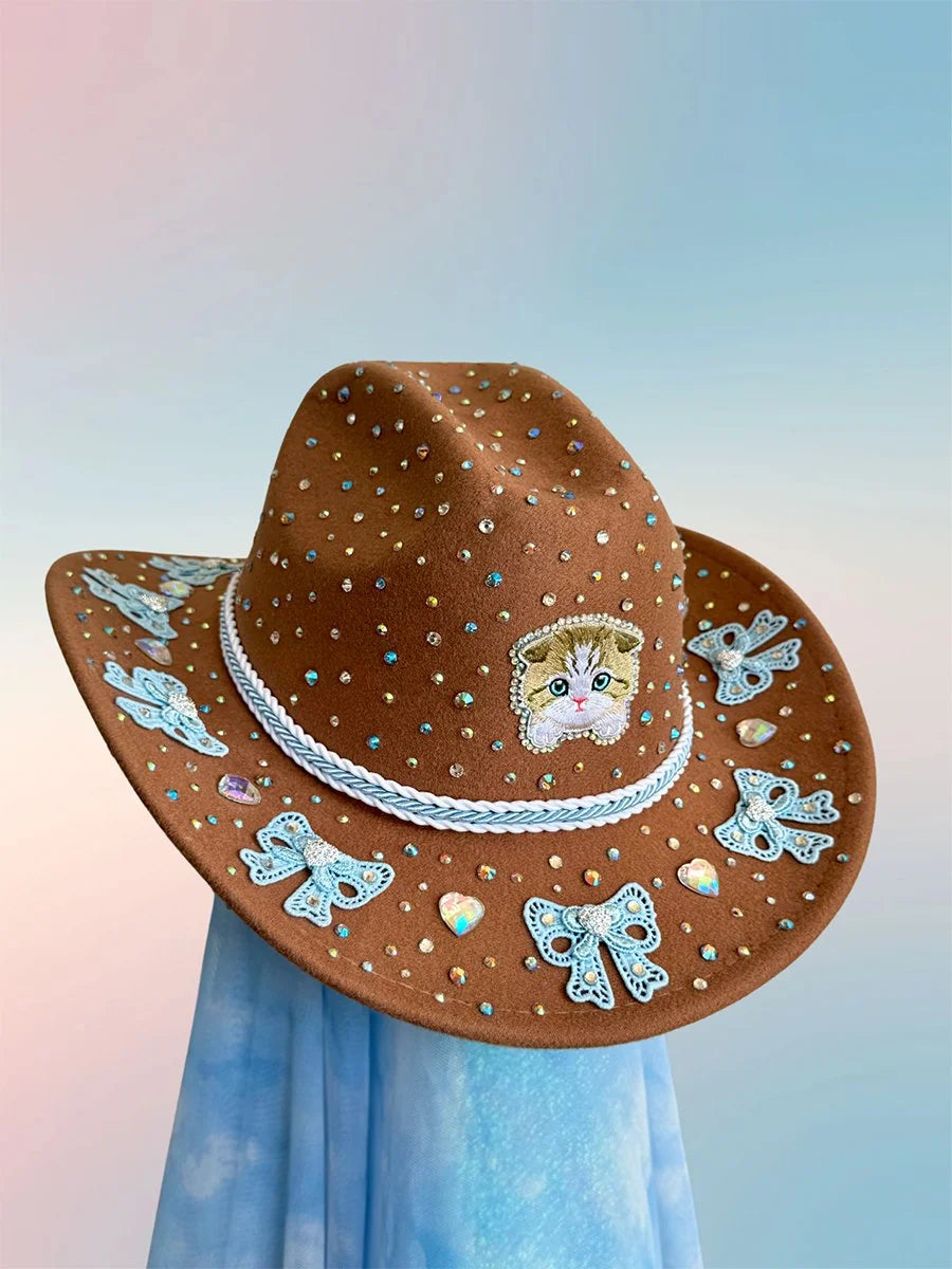 Front view of the Purrfectly Coquette cowboy hat in brown with cat motif, blue bow accents, and rhinestone embellishments.