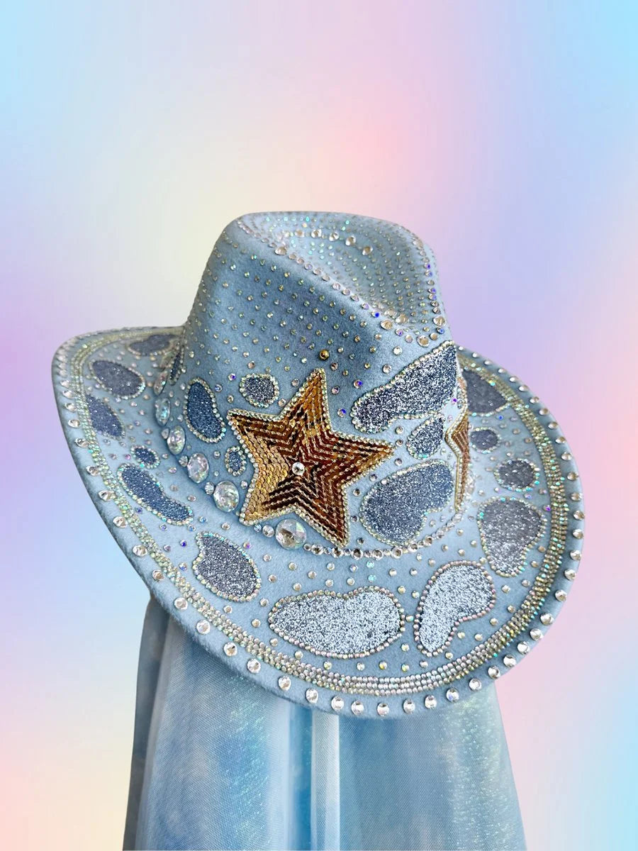 Front view of The Main Character cowboy hat in baby blue with rhinestones, gold stars, and glitter detailing.