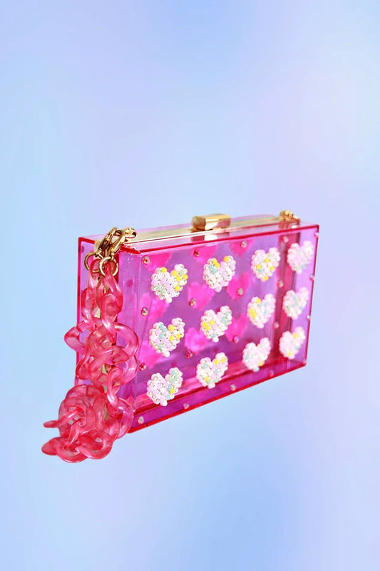 Neon pink acrylic clutch with iridescent rhinestone heart embellishments and pink acrylic chain strap.