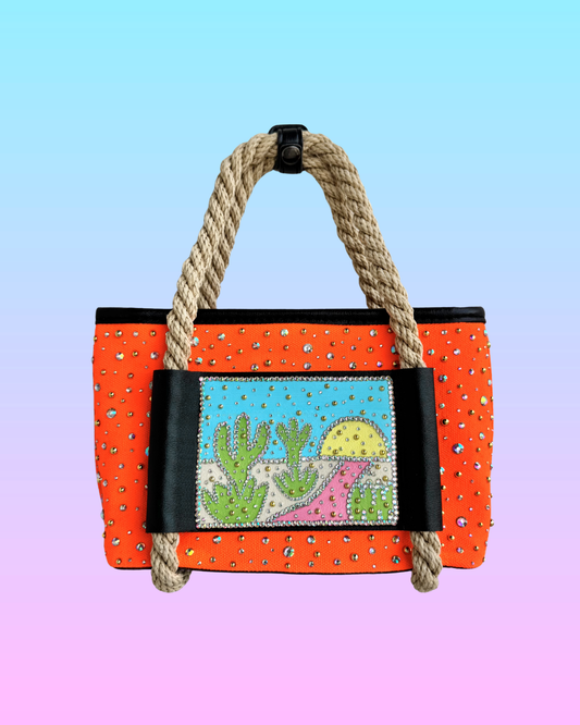 High Noon Mini Tote front view in neon orange with rhinestones, rope handles, and desert landscape panel.