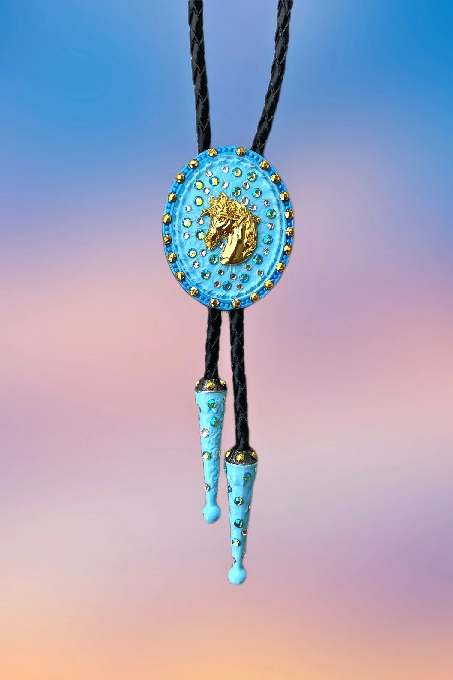 Front view of the Horse Head Bolo Tie with sky-blue pendant, gold horse centerpiece, and painted blue drop tips.