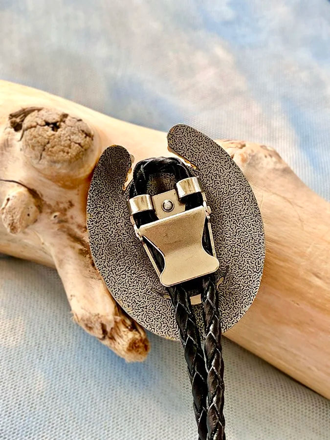Back view of the Horseshoe “J” bolo tie showing metal clasp hardware and braided black rope.