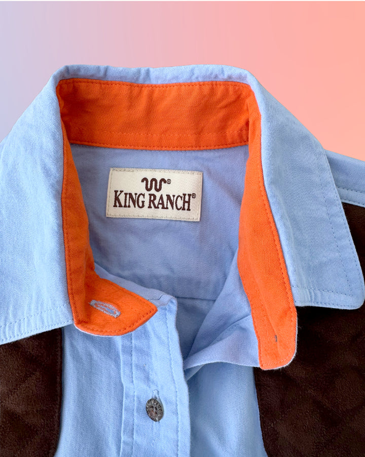 King Ranch shirt collar close-up showing the brand label, orange contrast lining, and light blue fabric.