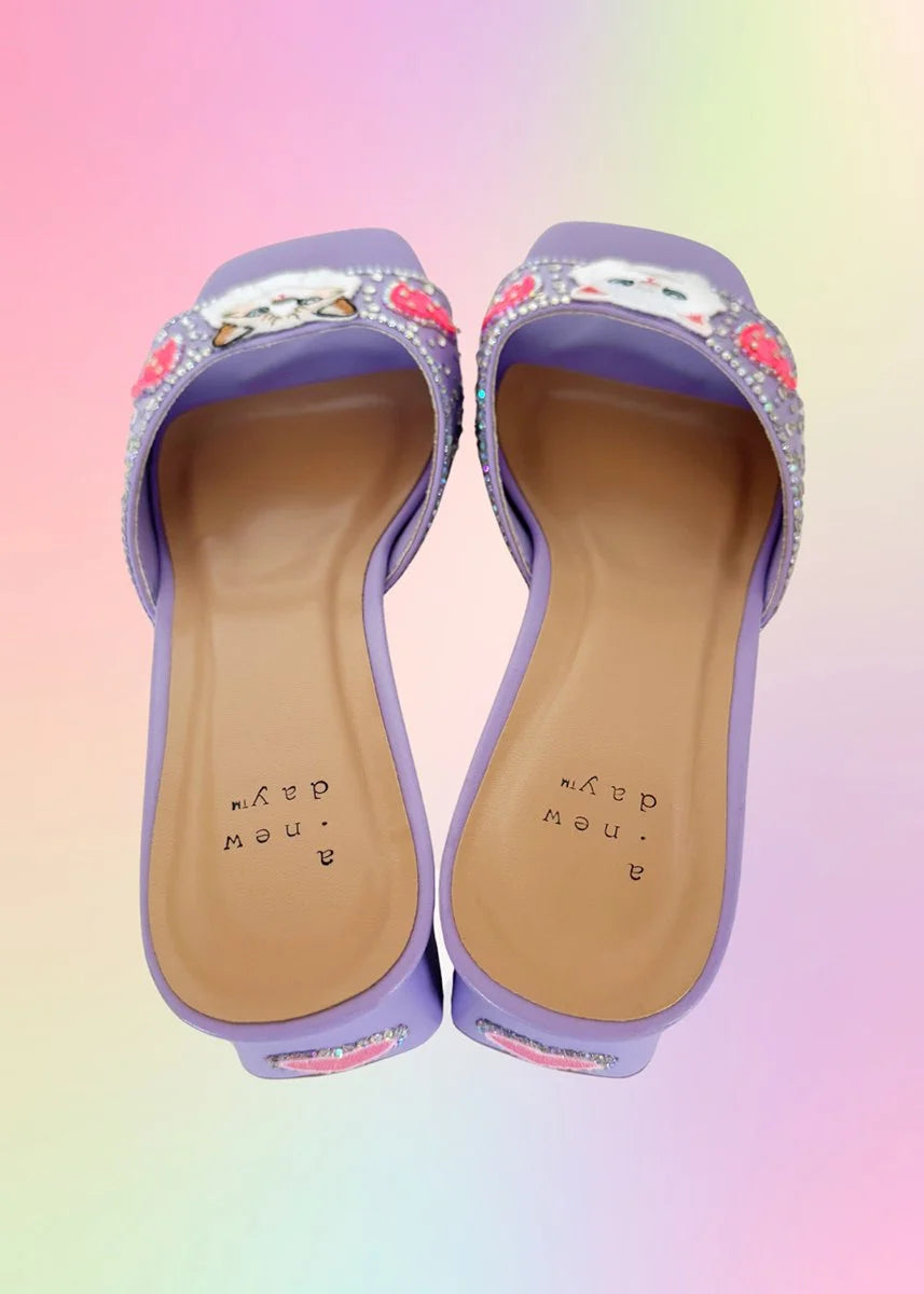 Angled view of lavender heels showcasing kitten patches and rhinestone detailing.