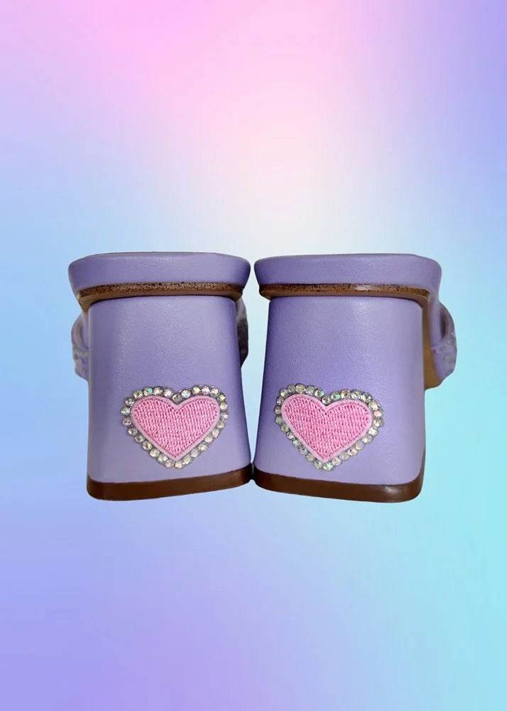 Back view of lavender heels featuring pink embroidered heart patches with rhinestones.