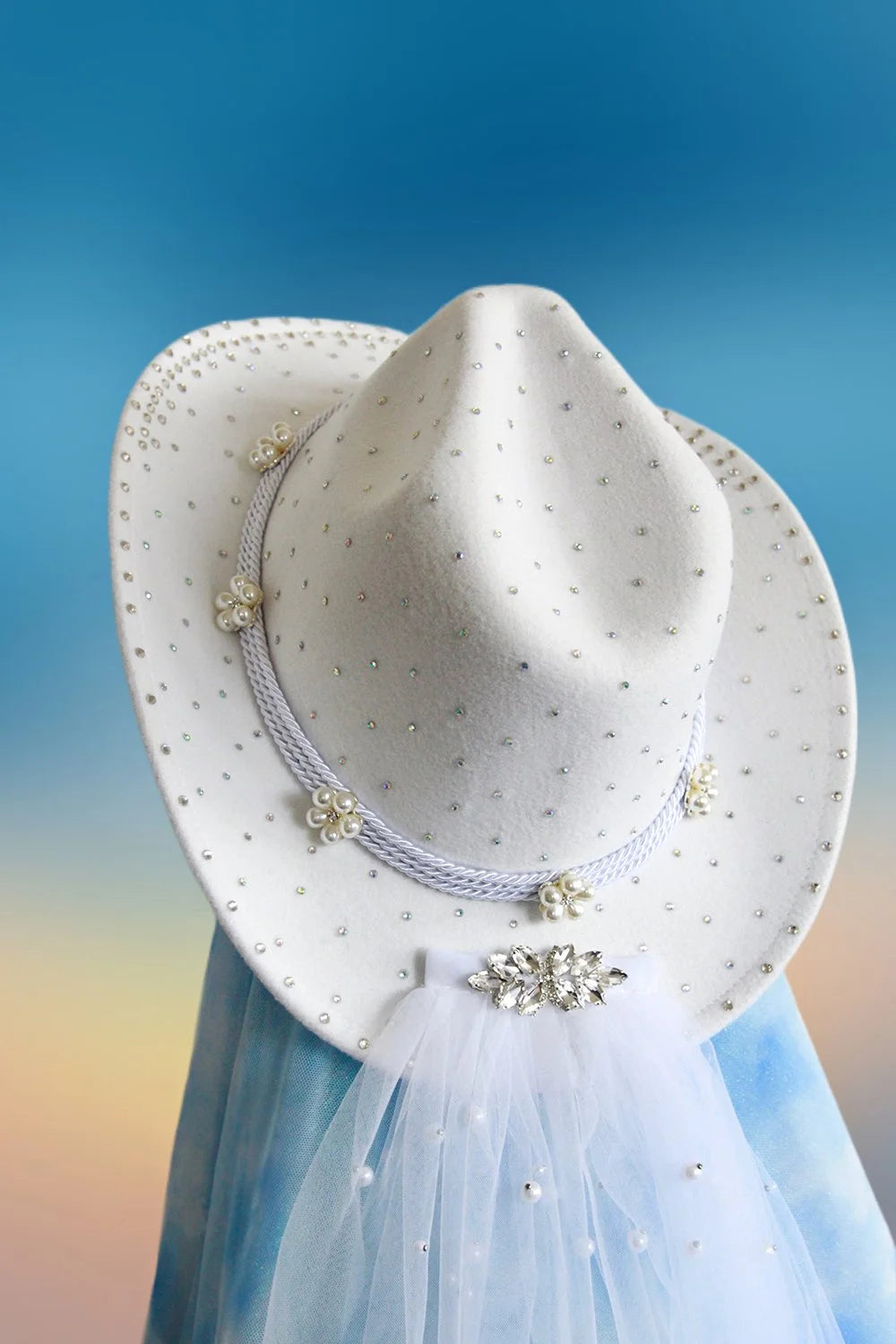 Close-up of pearl accents and rhinestones on white cowboy hat.