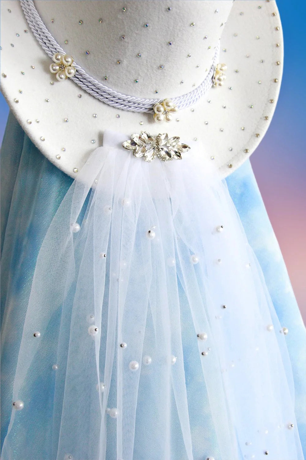 Detachable pearl tulle veil attached to white cowboy hat.