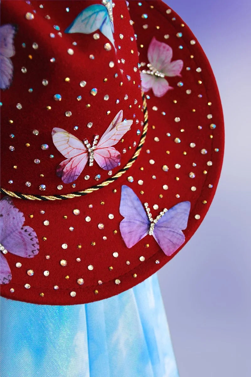 Close-up of maroon cowboy hat top brim with rhinestones and butterfly embellishments.