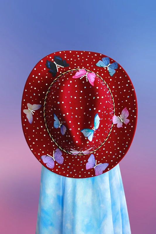 Close-up of maroon cowboy hat top brim with rhinestones and butterfly embellishments.