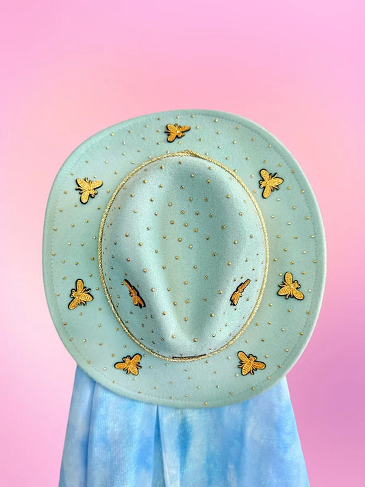 Top view of mint green cowboy hat decorated with gold bees and rhinestones.