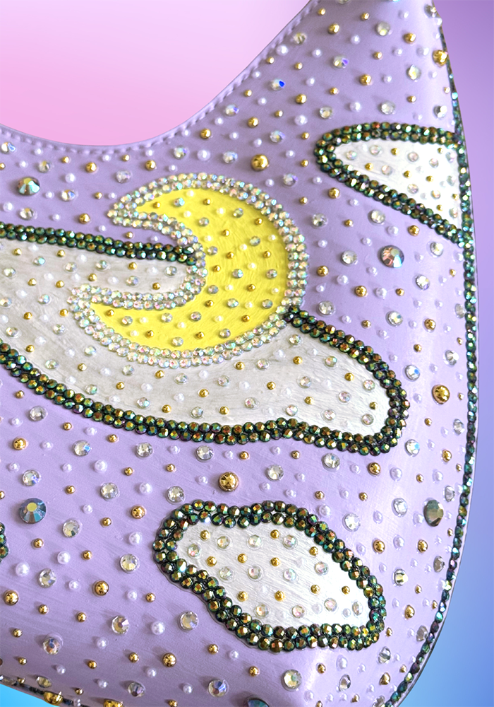 Close-up of painted yellow moon and sparkling rhinestone clouds on lavender vegan leather handbag.