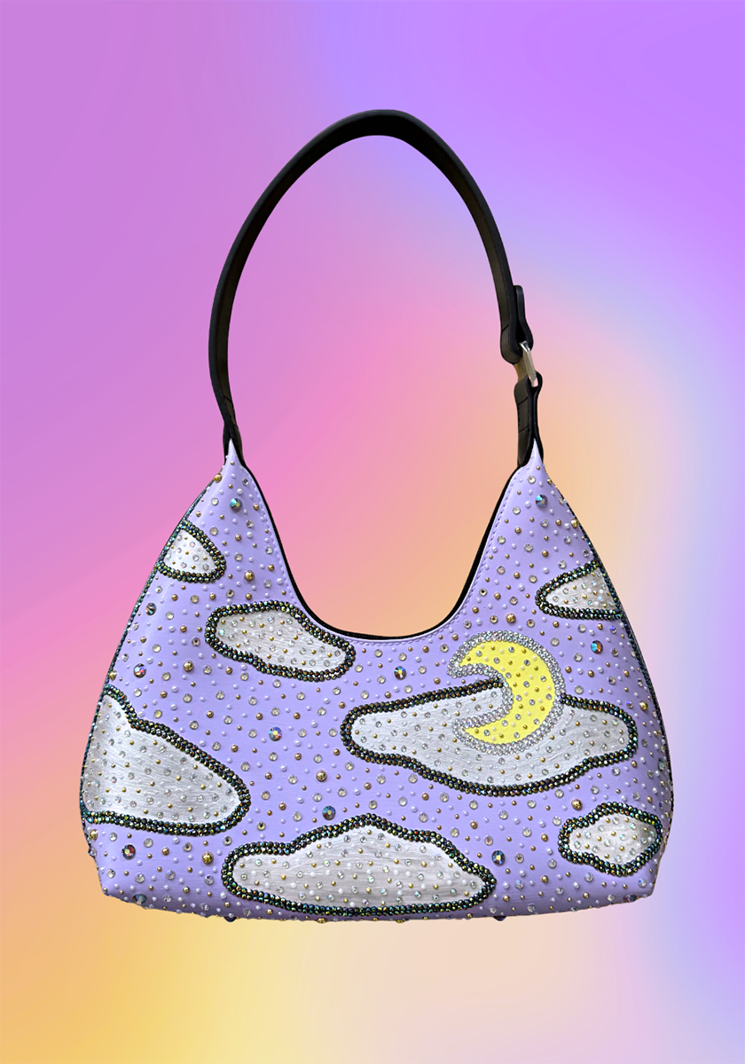 Full front view of lavender crescent-moon handbag with rhinestone clouds and painted details.