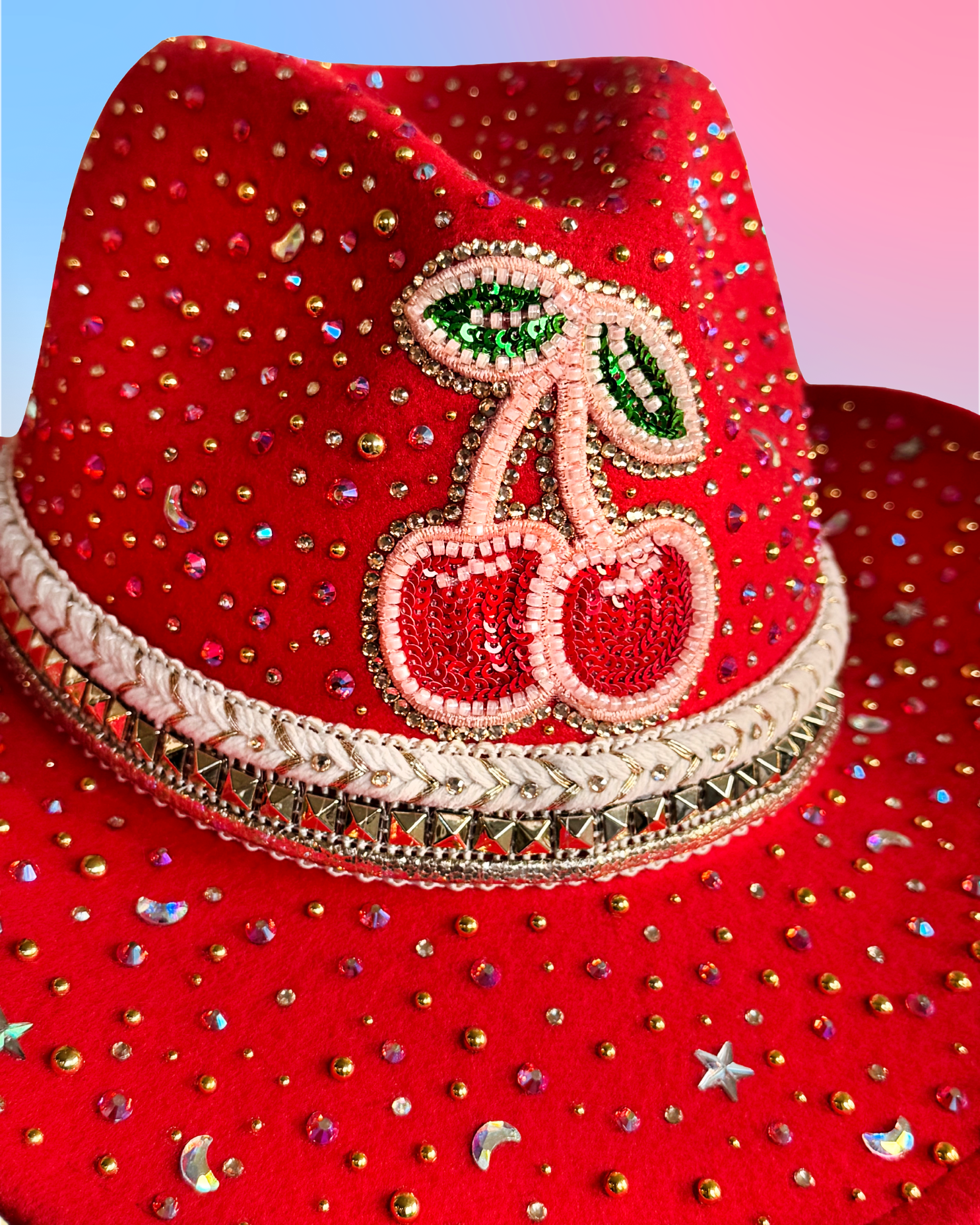 Close-up of beaded cherry patch and rhinestone embellishments on red cowboy hat.