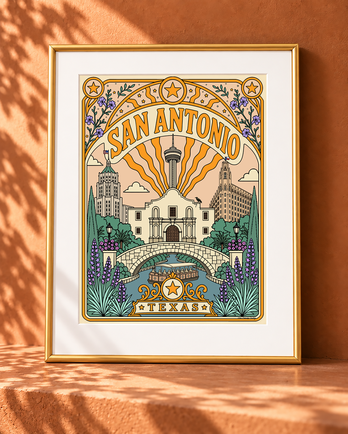 San Antonio Texas wall art displayed with a white mat in a slim modern gold frame against a warm adobe backdrop.