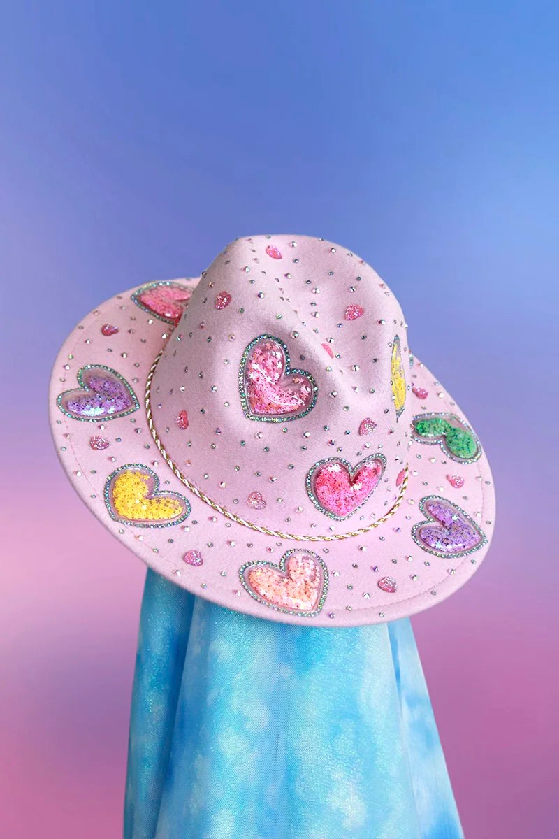 Pink pastel fedora with multicolor hearts, gold rope band, and scattered iridescent rhinestones, front angled view.