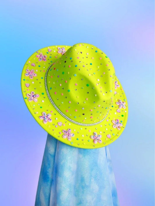 Tilted angle of neon green festival fedora covered in colorful confetti and gems.