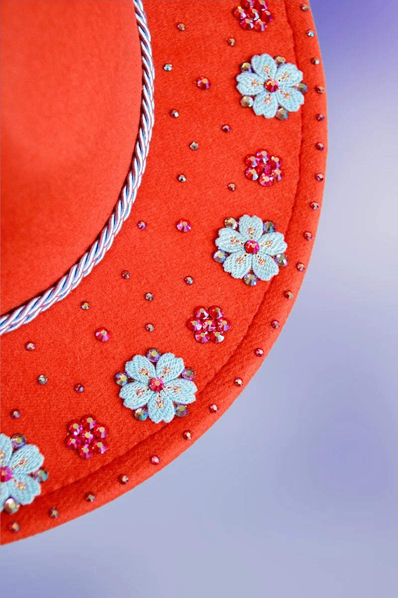 Close-up of embroidered blue flowers and sparkling pink rhinestones on the orange brim.