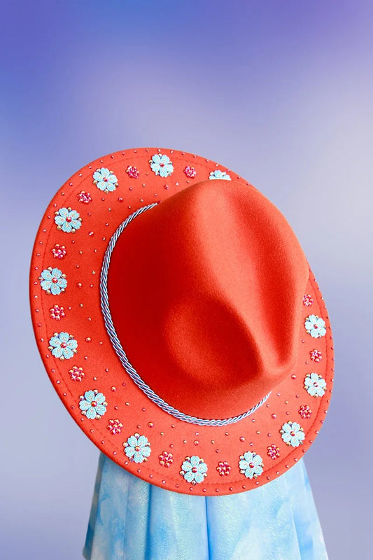 Front angled view of orange fedora with floral appliqués and scattered rhinestones.