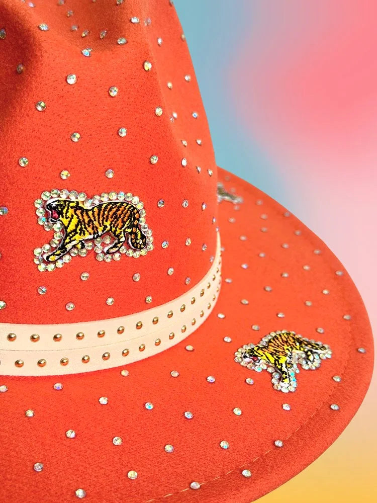 Close-up of the Sunset Prowl Fedora showing sequin tiger patches, hand-placed rhinestones, and the cream studded hat band. 